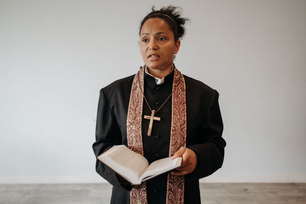 Demo Post 2 A female pastor in clerical attire stands with an open Bible in a church setting.