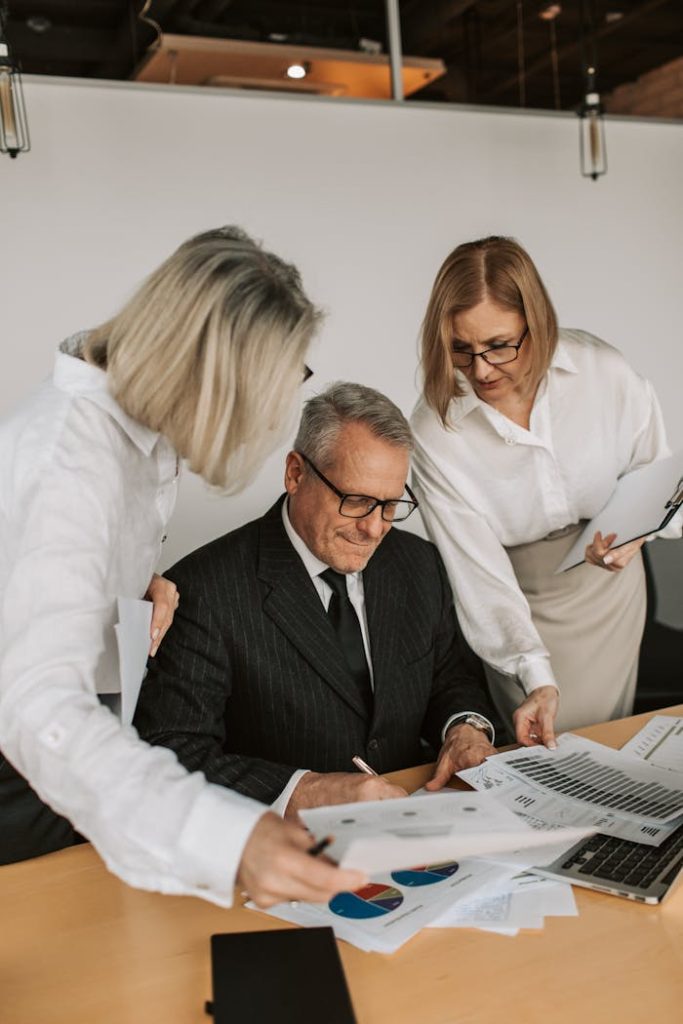 Demo Post 3 A senior businessman with colleagues discussing documents in a modern office.